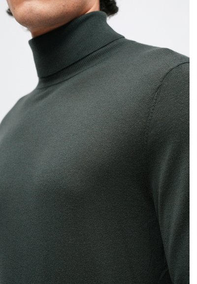 Temno zelena turtleneck pulover iz teksturirane tkanine, ki ima oprijet kroj in rebrast ovratnik, kar poudarja gladko površino.