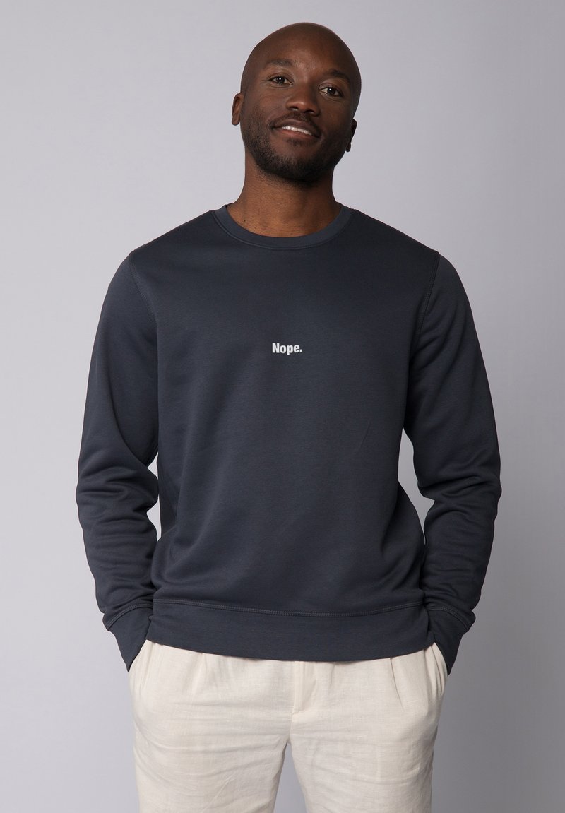 Donkergrijze sweatshirt van zachte stof met een ronde hals en lange mouwen, met de tekst "Nope." in het wit gedrukt op de voorkant.