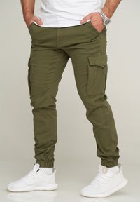 Olive green cargo pants with elasticized cuffs, side pockets, and a relaxed fit. Made of durable fabric with a smooth texture.