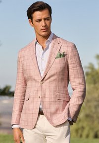 Blazer à carreaux rose clair avec un tissu texturé, doté d'une fermeture à un bouton et de deux poches avant, associé à une chemise bleu clair.