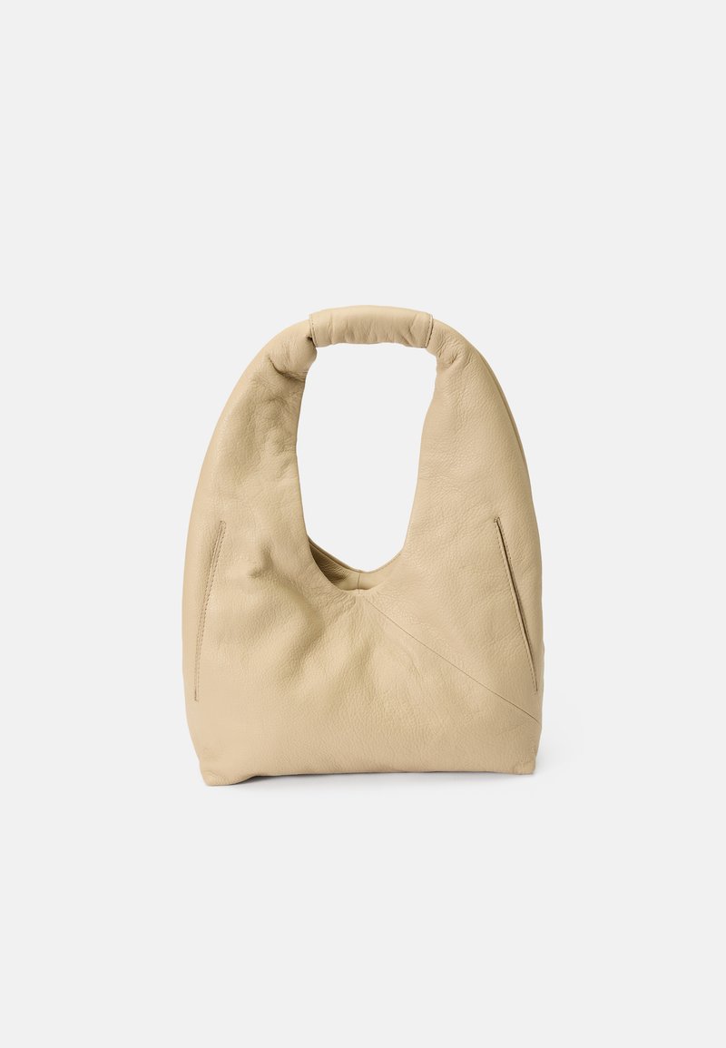 Sac à bandoulière en cuir beige avec une forme douce et arrondie et une poignée rembourrée. Comprend deux poches zippées latérales et des détails de couture minimalistes.