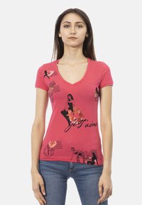 T-shirt rose en V, fabriqué en coton, avec des impressions graphiques noires de mannequins et du texte, agrémenté d'accents métalliques sur une coupe ajustée.