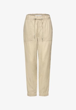 Pantalon beige avec cordon de serrage, taille et poignets élastiques, comportant deux grandes poches plaquées à l'avant et une coupe fuselée décontractée.