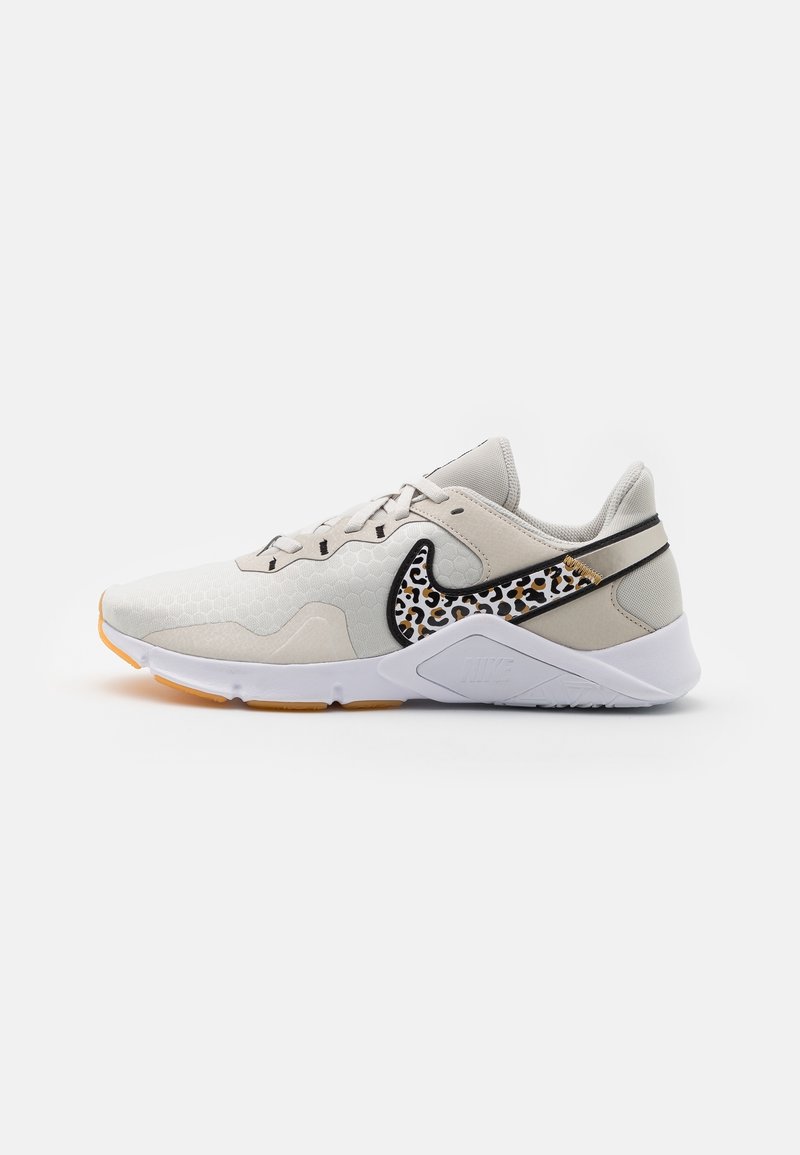 White athletic shoe with a textured surface, black and leopard print accents, and a thick white sole with a gum rubber outsole.