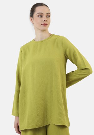 Maglietta a maniche lunghe, con scollatura rotonda, in tessuto testurizzato di colore verde chiaro. Vestibilità rilassata con orlo dritto. Design minimalista senza dettagli visibili.