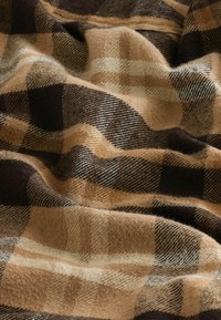 Brown and tan plaid fabric with a mix of large and small checks. Soft, textured weave with a warm, wool-like appearance.