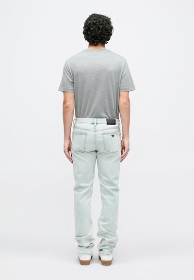 Ανοιχτό μπλε τζιν με ίσια γραμμή, εμφανείς ραφές και δερμάτινο ταμπελάκι στη μέση, συνδυασμένα με γκρι κοντομάνικο μπλουζάκι.