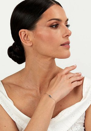 Silberarmband mitTürkis-Akzenten, das am Handgelenk getragen wird. Das Design zeichnet sich durch eine zarte Kette und schlichte, moderne Ästhetik aus.