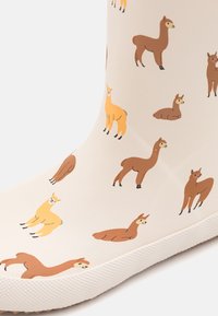 Bottine en caoutchouc blanc cassé avec une semelle blanche texturée, ornée d'illustrations colorées de lamas dans diverses poses et couleurs.