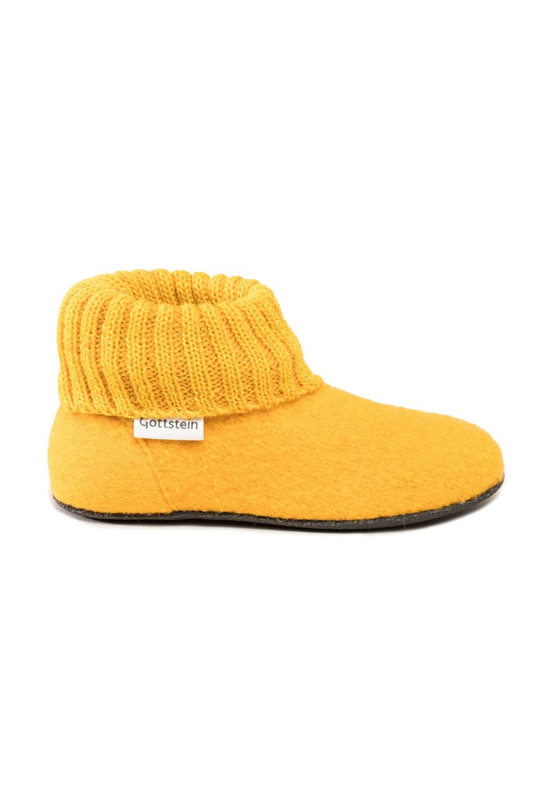 Weiche gelbe Hausschuhe mit gestricktem Bündchen und schwarzem Sohle, beschriftet mit "Gottstein", seitlich auf weißem Hintergrund gezeigt.