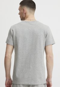Graues Kurzarm-T-Shirt mit gerippter Textur, Rundhalsausschnitt und geradem Saum. Der Stoff wirkt weich und leicht.