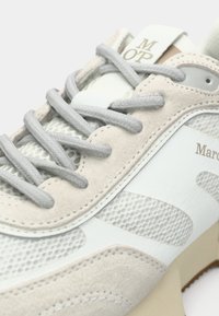 Ανοιχτό γκρι αθλητικό παπούτσι που συνδυάζει σουέντ και πλέγμα υλικά, με παστέλ αποχρώσεις, επίπεδα γκρι κορδόνια και ανάγλυφο λογότυπο στο πλάι.