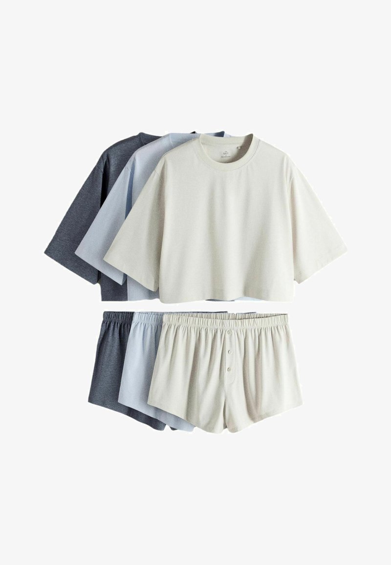 Trei seturi de îmbrăcăminte casual pentru relaxare, cu bluze cu mâneci scurte și croială scurtă și pantaloni scurți cu talie elastică, în culorile crem, albastru deschis și gri închis.