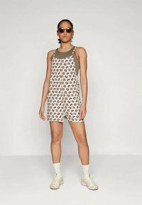 Ziedu raksta pārvalki šortos ar vieglu audumu un tumši zaļu augšējo daļu. Iespējamas regulējamas siksnas un priekšējā pogu aizdare.