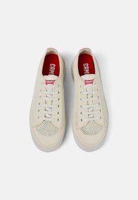 Sneaker beige con un design in rete, suole in gomma, lacci bianchi piatti e soletta rossa con logo "CAMPER".