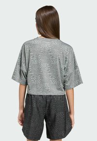 Strihané sivé tričko s leopardím vzorom a voľnými rukávmi. Kombinované s čiernymi šortkami, oboje vyrobené z mäkkej, štruktúrovanej látky.