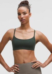Bralette verde oliva con tirantes finos, textura suave, forma rectangular y diseño minimalista, combinado con leggings de cintura alta beige.