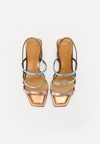 Sandales à talons hauts en cuir brun clair avec un bout carré, dotées de fines brides bleu et vert, et d'une bride de cheville métallique rose avec une petite boucle.