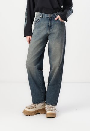 Light blue denim jeans with a loose fit and straight legs. Paired with chunky, beige platform shoes featuring a fur accent.