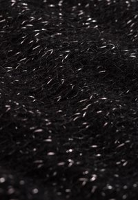 Czarna tkanina o fakturze z metalicznymi srebrnymi przędzami wplecionymi w całość, tworząca miękki, puszysty wygląd z lekko błyszczącym wykończeniem.