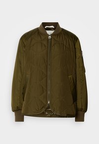 Veste bomber matelassée vert olive avec fermeture éclair à l'avant, col et poignets côtelés, et poche zippée sur la manche gauche.