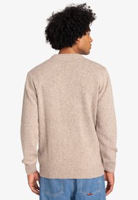 Beige gebreide trui met ronde hals, geribde manchetten en zoom, met een gestructureerd oppervlak en een casual pasvorm.