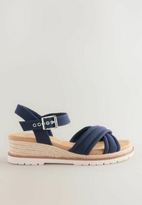 Sandale compensée bleu marine avec brides croisées en tissu, boucle à la cheville, semelle intermédiaire enveloppée de jute beige et semelle extérieure en caoutchouc blanc.