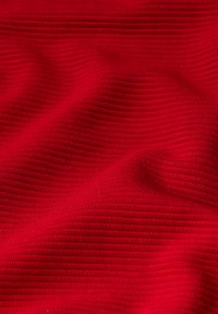 Tessuto rosso con texture, caratterizzato da un motivo a coste, che mostra pieghe e grinze, con una superficie liscia e un colore vivace.