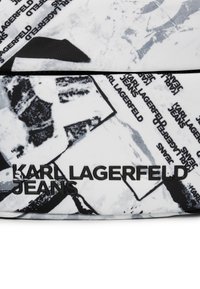 Teksturna tkanina z abstraktnimi črno-belimi vzorci in črnim logotipom "KARL LAGERFELD JEANS" na žepku z zadrgo.