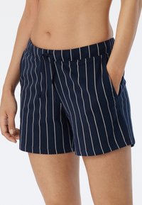 Mørkeblå bomullsshorts med hvite vertikale striper, snøring i livet og sidelommer. Glatt tekstur med en uformell passform.