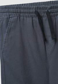 Szare spodnie dresowe z mieszanki bawełny, wyposażone w elastyczny pas, sznurek ściągający oraz dwie boczne kieszenie. Powierzchnia ma teksturowane wykończenie.