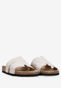 Sandalias deslizantes de corcho en color blanco roto con un upper suave, que presenta detalles troquelados y una suela marrón texturizada para mayor agarre y comodidad.