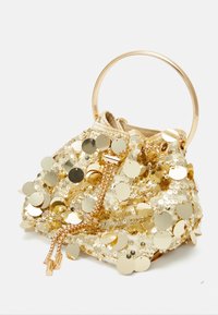 Złota torebka z cekinami, z okrągłym metalowym uchwytem, posiadająca zapięcie na ściągacz oraz dekoracyjne akcenty w postaci łańcuszka. Teksturowana powierzchnia z efektami odbicia światła.