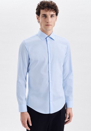 Lyseblå langærmet skjorte med slim fit, button-down krave og glat stof. Har en buet kant og standard knaplukning foran.