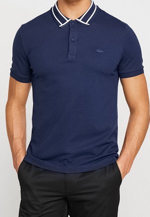 Marineblaues Polohemd mit Zweiknopf-Blende, gestreiftem Kragen und gesticktem Logo. Hergestellt aus weicher Baumwolle, mit schmaler Passform.