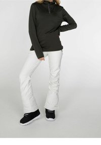 Maglietta nera a maniche lunghe con colletto a mezza zip, abbinata a pantaloni da sci bianchi e stivaletti neri con suole bianche, su uno sfondo neutro.