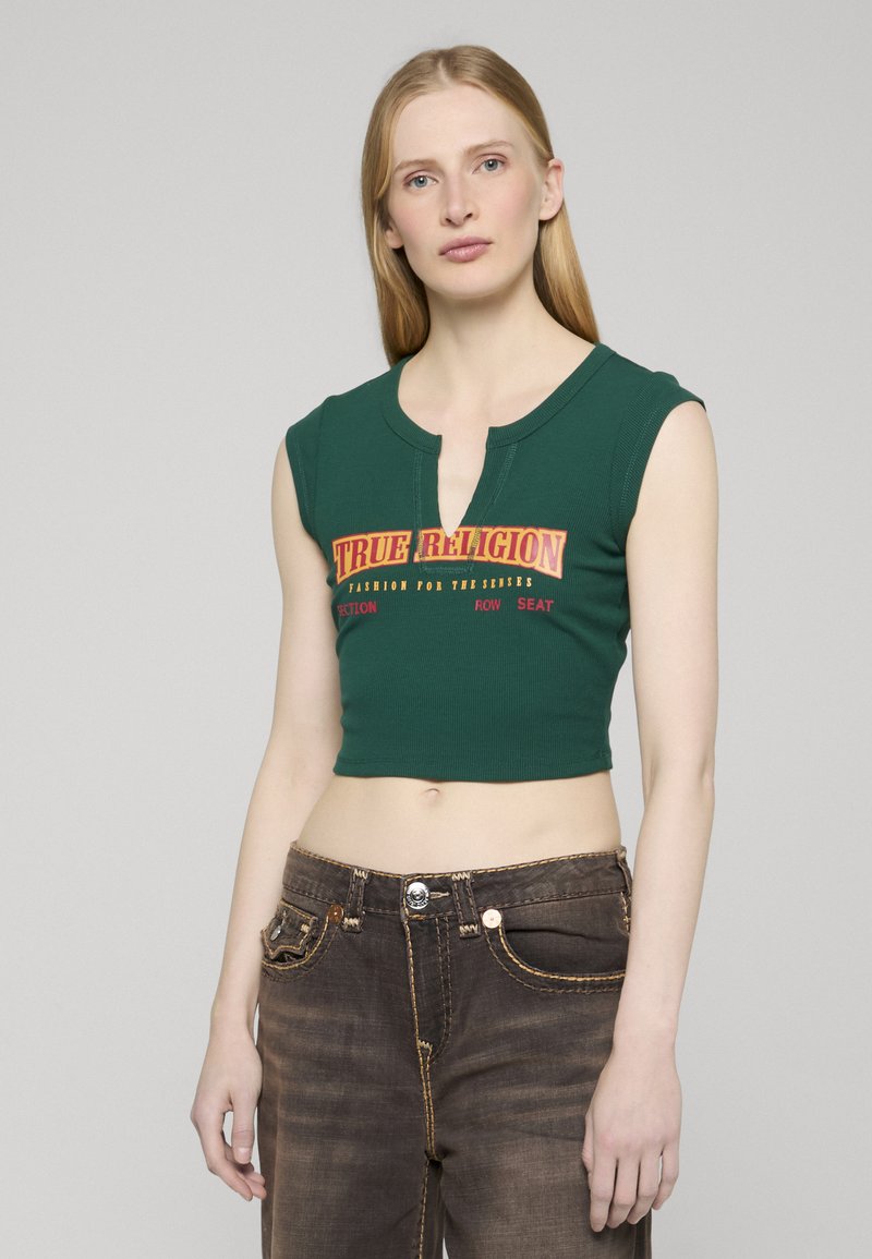 Zelený krátký top s kulatým výstřihem a předním zapínáním. Obsahuje výrazné logo "TRUE RELIGION" vytištěné červeně a žlutě.