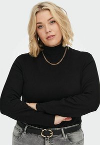 Črn pulover z visokim ovratnikom in dolgimi rokavi; mehak material. Ujemajoč se z svetlo sivo jeans hlačami in črnim pasom z zlatim okroglim sponko.