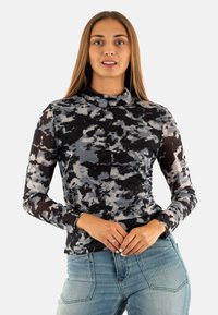 Top a maniche lunghe con collo alto in un motivo astratto di nero, grigio e bianco, caratterizzato da un design aderente e un tessuto morbido e elasticizzato.