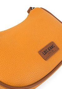 Bolso de cuero sintético amarillo texturizado con forma curva, ribete marrón y una etiqueta de logo con "LOIS JEANS" grabado en el cuero.