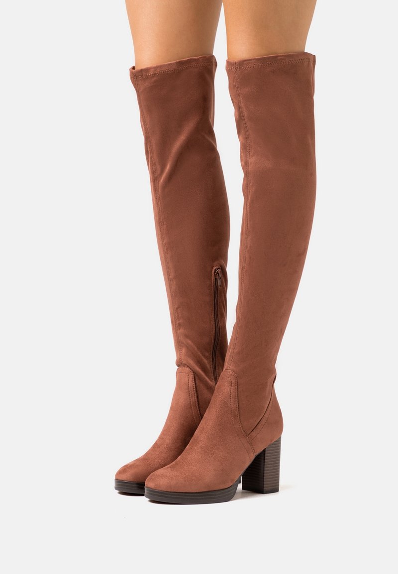 Bottes marron montantes jusqu'au genou en daim souple, avec un talon épais et une fermeture éclair latérale ; design élégant et texture lisse.