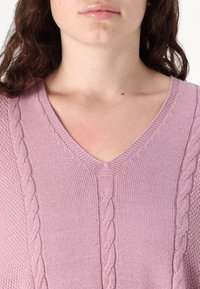 Ανοιχτό ροζ πλεκτό πουλόβερ με V-λαιμόκοψη, που διαθέτει υφασμάτινα καλώδια κατά μήκος των πλευρών και λείο σώμα.