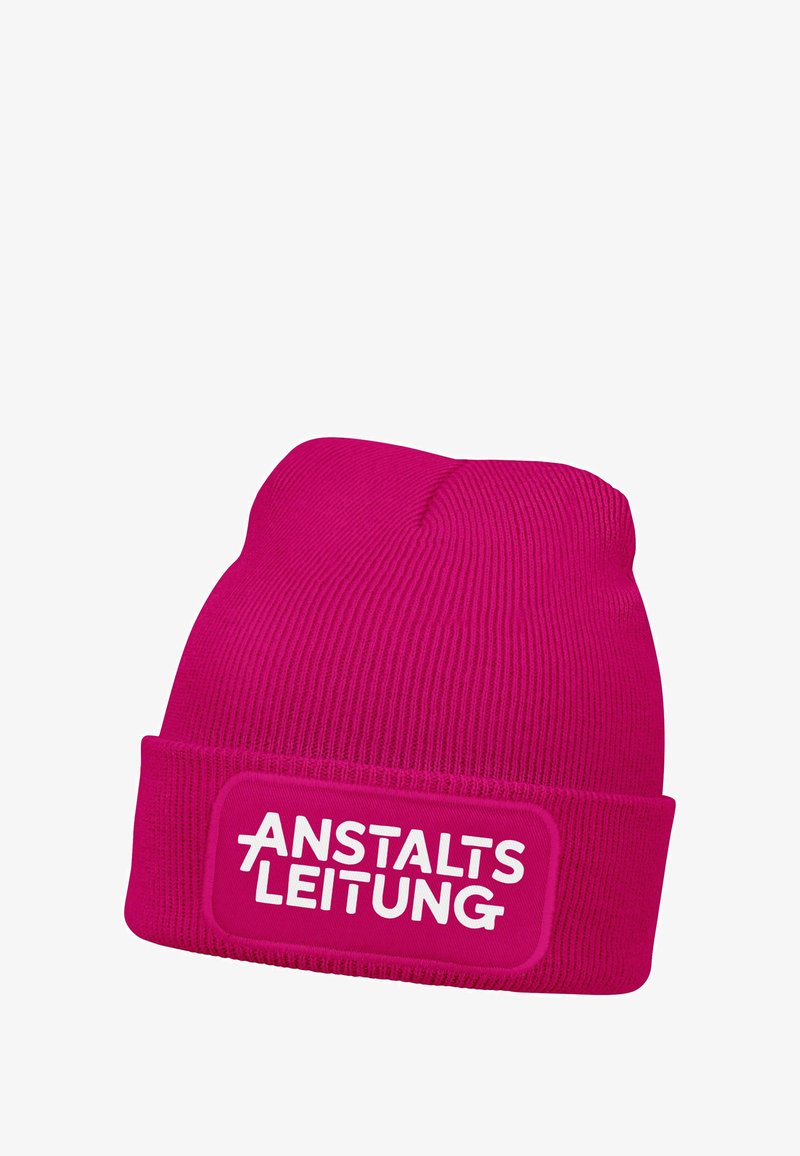 Pink knitted beanie with a textured ribbed design and a folded cuff featuring a rectangular patch with the text "ANSTALTSLEITUNG" in white.