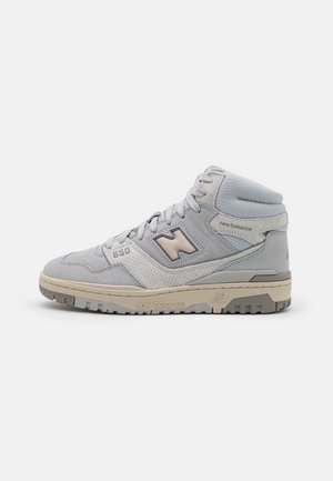 Baskets montantes New Balance 650 gris et beige avec lacets, col matelassé à la cheville et semelle en caoutchouc texturée sur fond blanc.