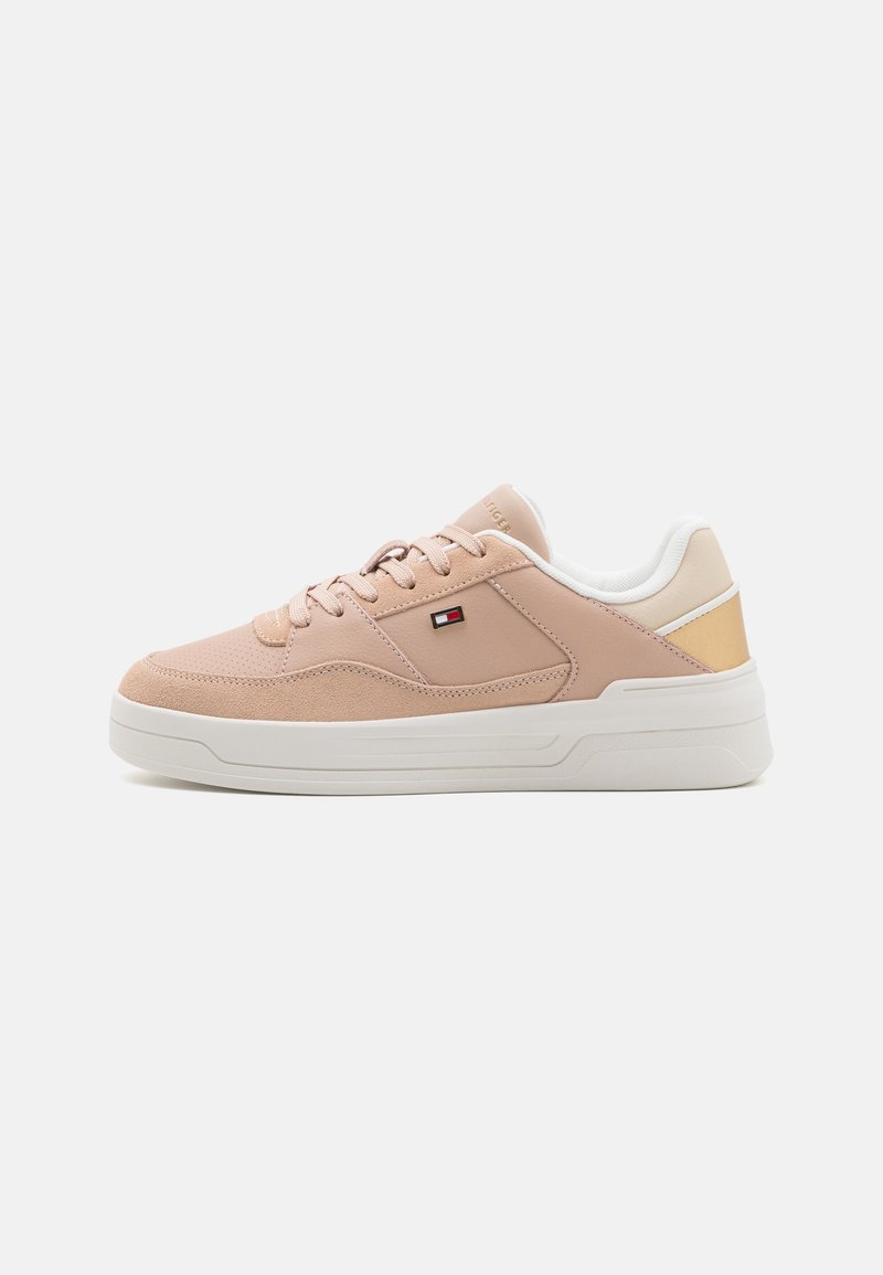Baskets basses beige et rose clair avec semelle blanche, devant lacé, et petit logo rectangulaire sur le panneau latéral.