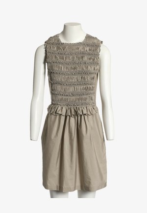 Robe beige sans manches avec corsage froncé et volanté, taille froncée et jupe lisse en forme trapèze exposée sur un mannequin blanc.
