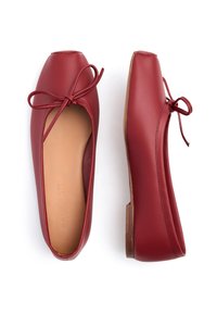 Rode leren ballerina's met vierkante neuzen, kleine strikjes bovenop en beige binnenzolen, weergegeven vanuit bovenaanzicht en zijaanzicht op een witte achtergrond.