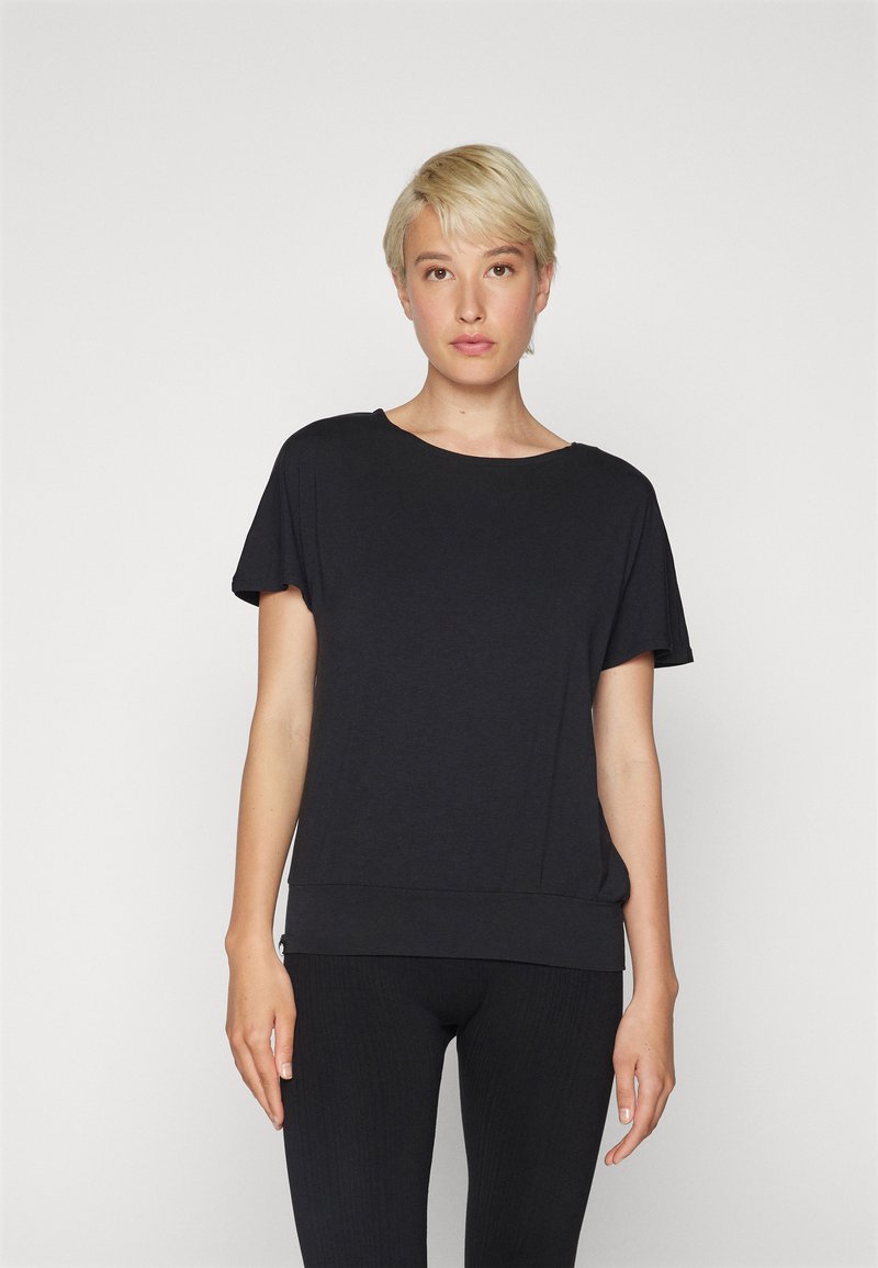 T-shirt nera a maniche corte con vestibilità rilassata e scollatura rotonda, caratterizzata da una texture morbida e un orlo leggermente più lungo in vita.