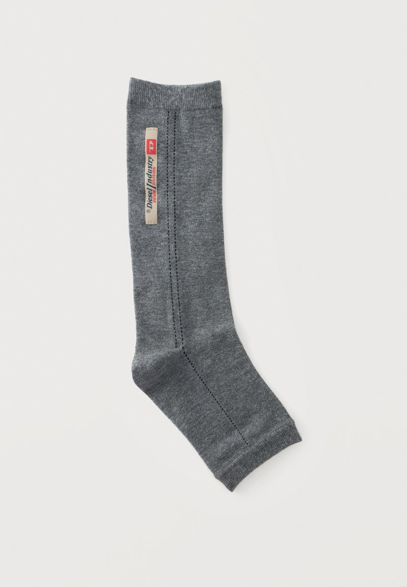 Chaussette grise unique avec des coutures visibles et une étiquette beige verticale Diesel Industry près du haut, présentée sur un fond blanc uni.