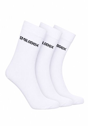 Drei weiße Crew-Socken mit schwarzem Textlogo „SMILODOX“ nahe des oberen Bündchens, nebeneinander auf weißem Hintergrund angeordnet.